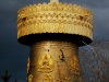 sha-golden-prayer-wheel-against-a-darkened-sky.jpg